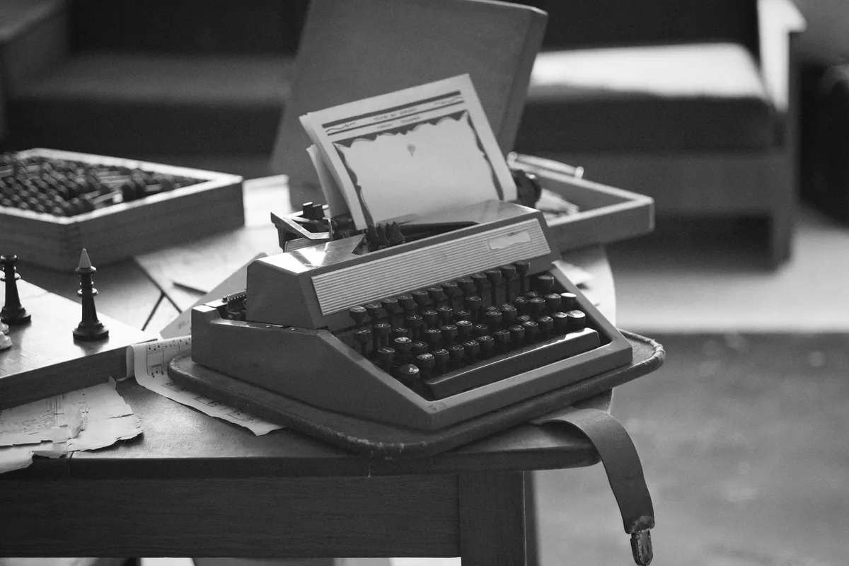 A vintage typewriter on a wooden desk with a manuscript page showing speculative fiction terms