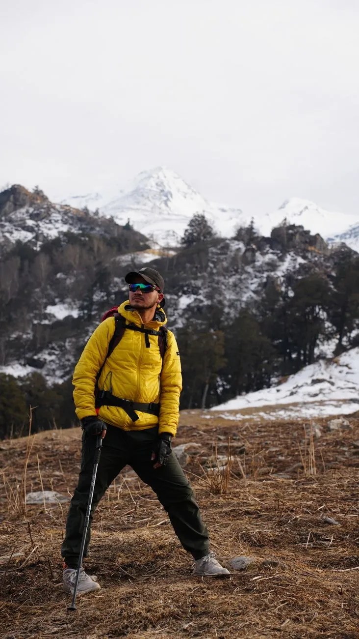 A Bhutanese tour guide assisting a traveler with trekking gear at the base of the Tiger’s Nest trail
