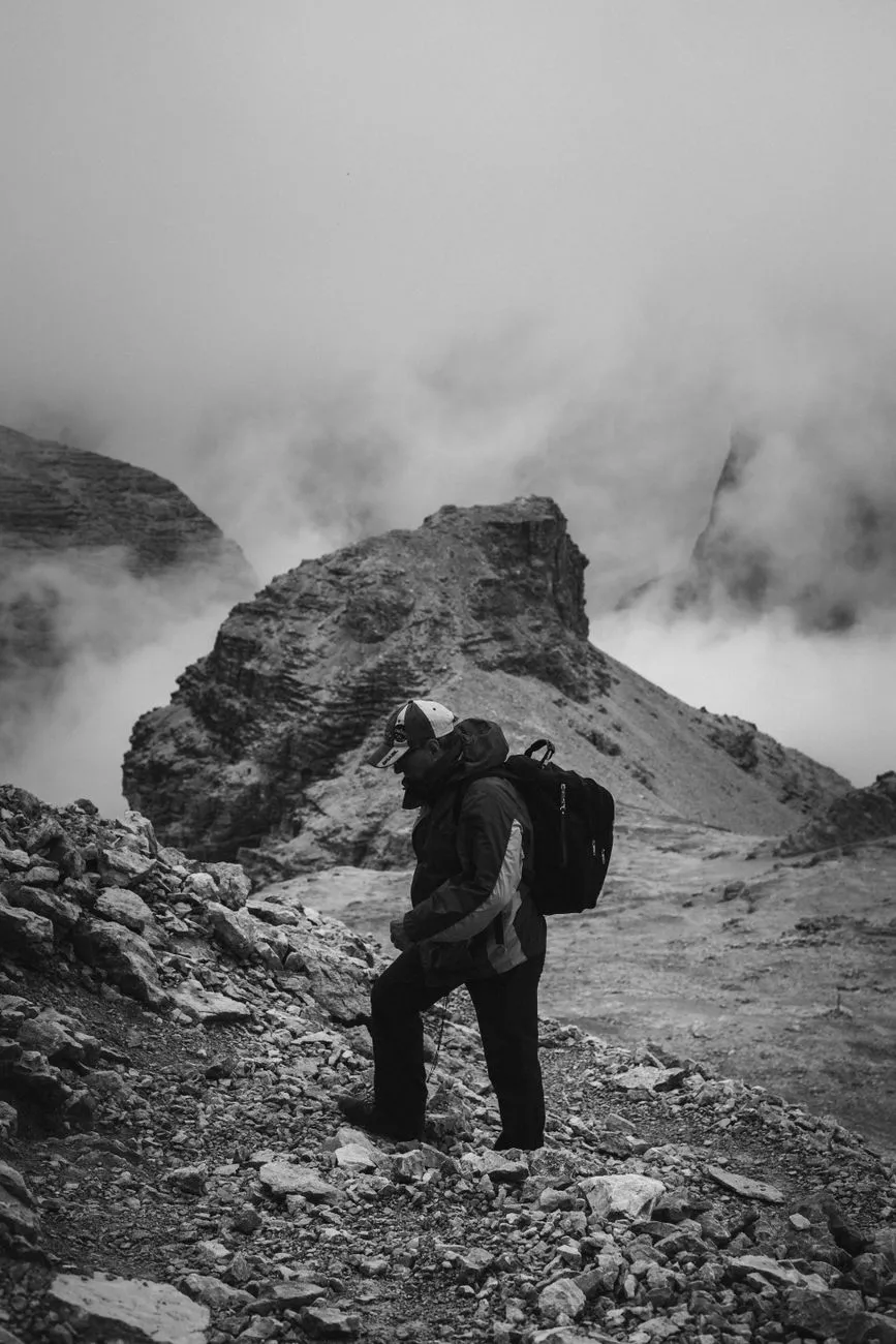 A solo hiker standing on a ridge overlooking a vast mountain range