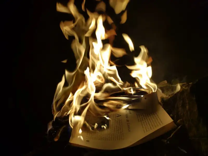 Verbrannte Buchseiten, Flammen zerstören altes Wissen, dunkle, atmosphärische Aufnahme