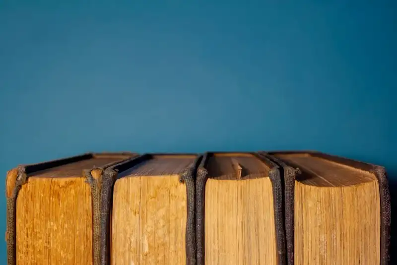 Nahaufnahme der Hände eines Fore-edge-Malers, der mit feinen Pinseln Aquarell auf die aufgefächerten Seiten eines antiken Buches aufträgt
