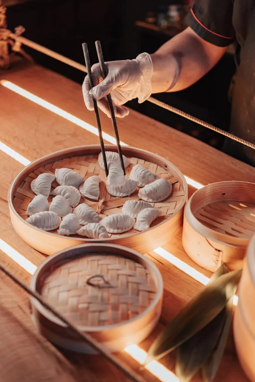 A server delivering steaming dim sum to a table