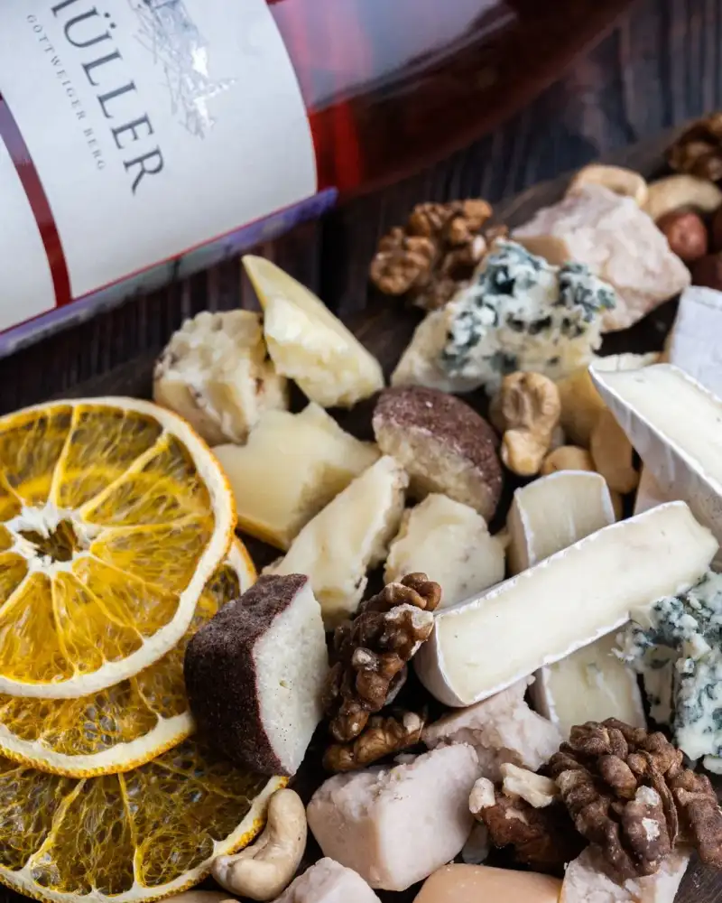 A cheese board with nuts, cured meats, and pickles