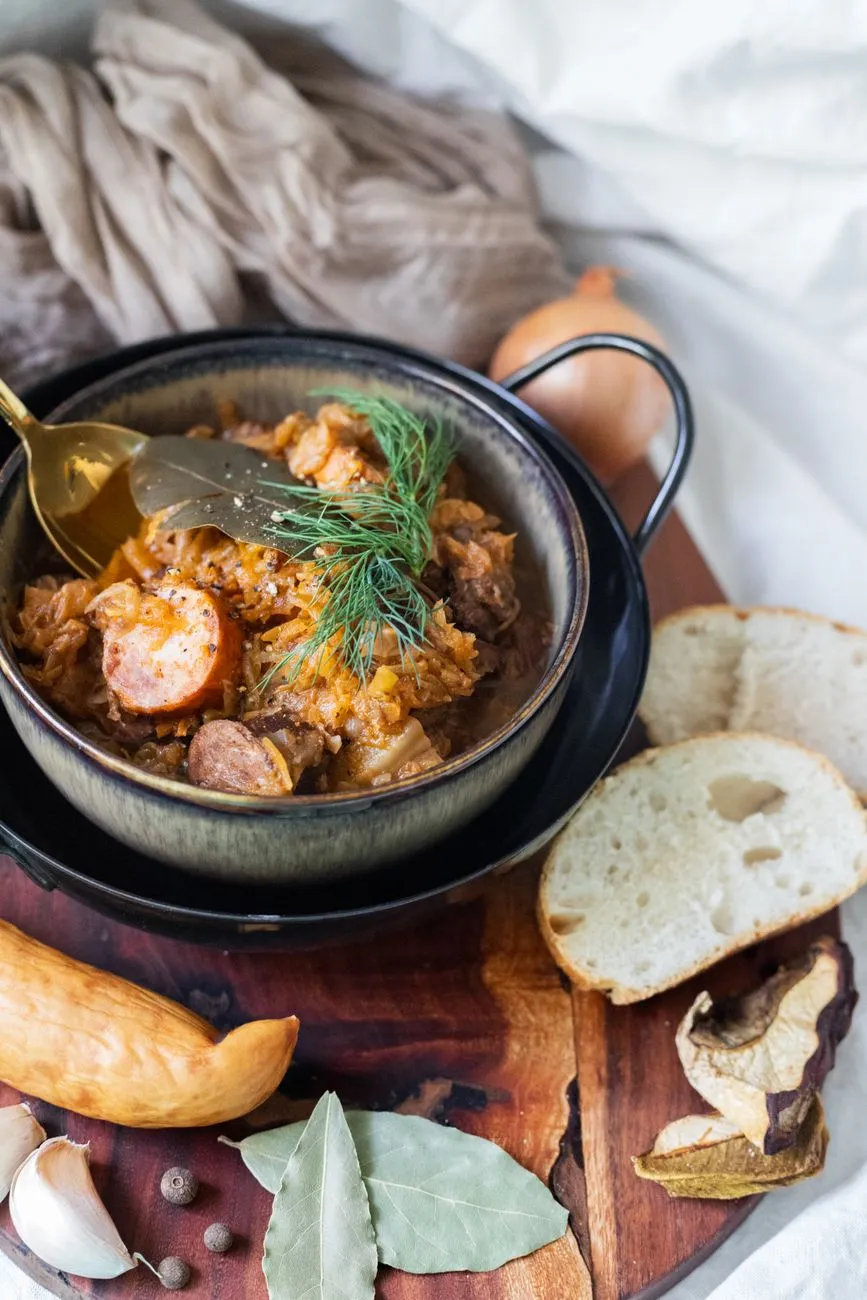 A wooden table with a jar of sauerkraut and a side of sausages