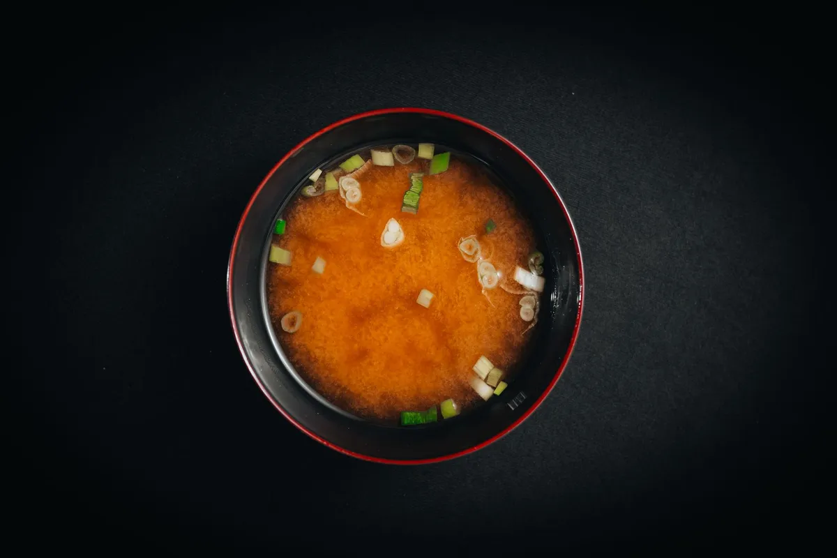 A bowl of miso soup with tofu and seaweed garnish