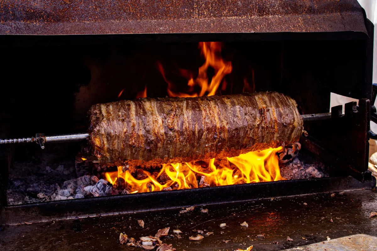 A traditional Turkish kebab being cooked on a grill