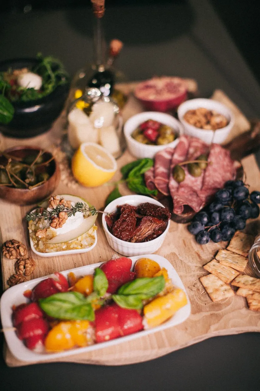 A rustic wooden table laden with an array of colorful tapas dishes, including olives, cured meats, and fried seafood
