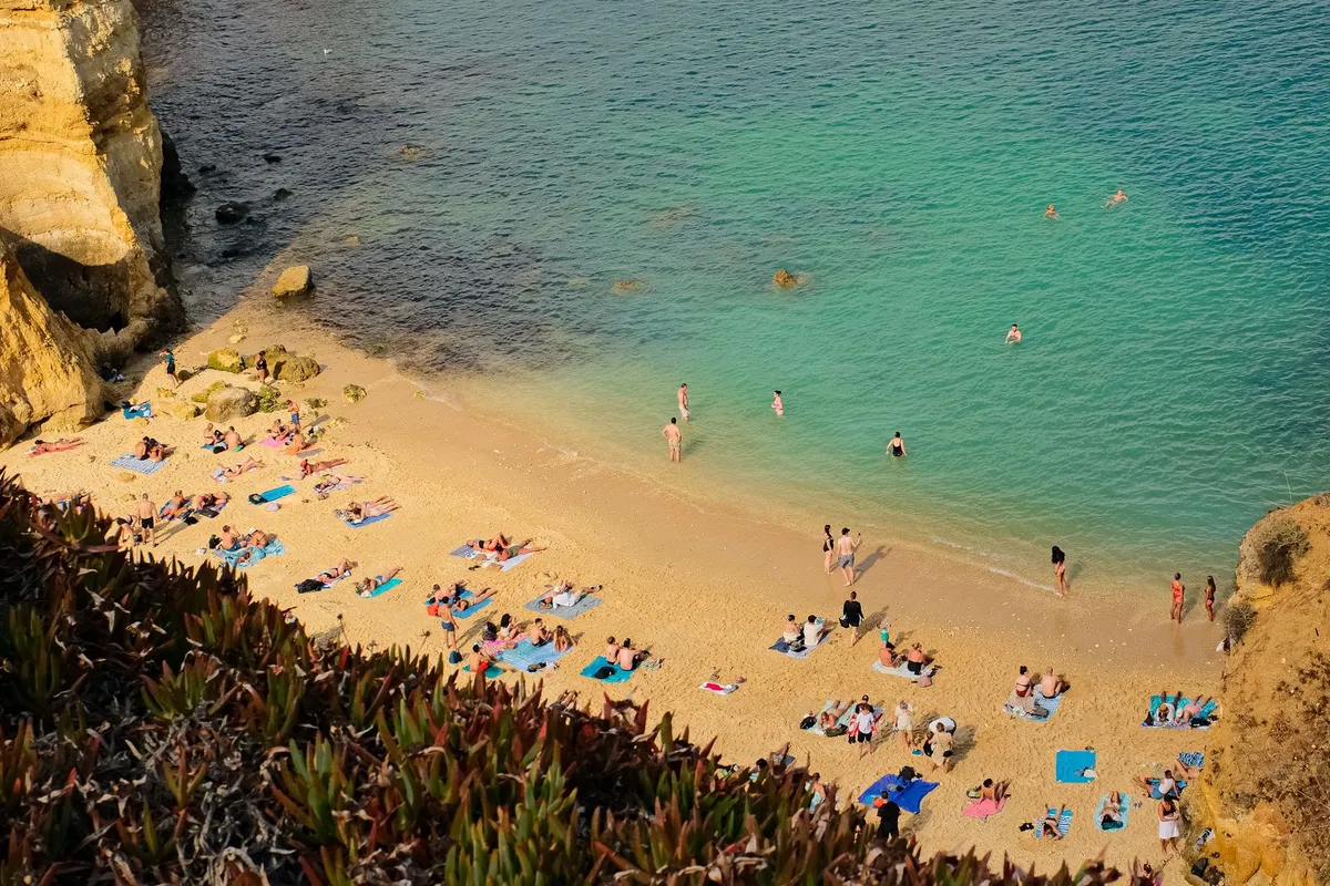 Algarve cliffside road with golden limestone arches and turquoise water