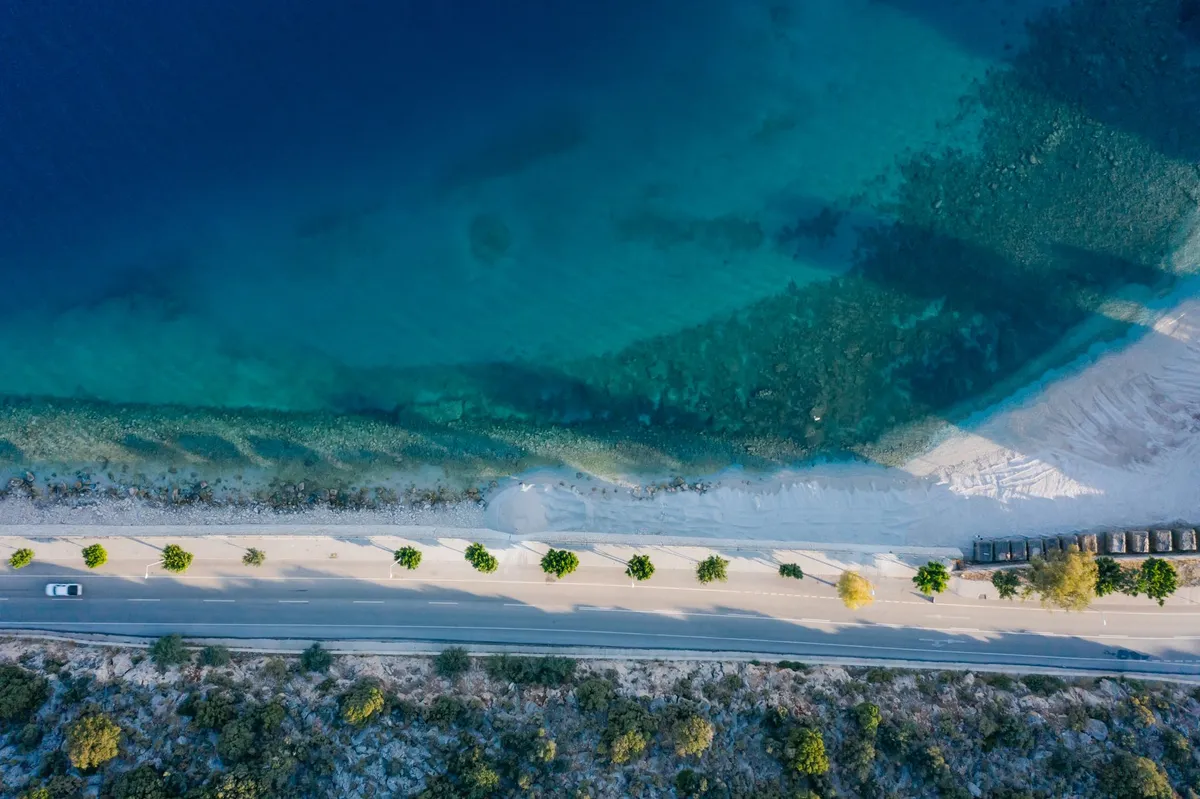 Coastal road at sunset with winding path and turquoise water