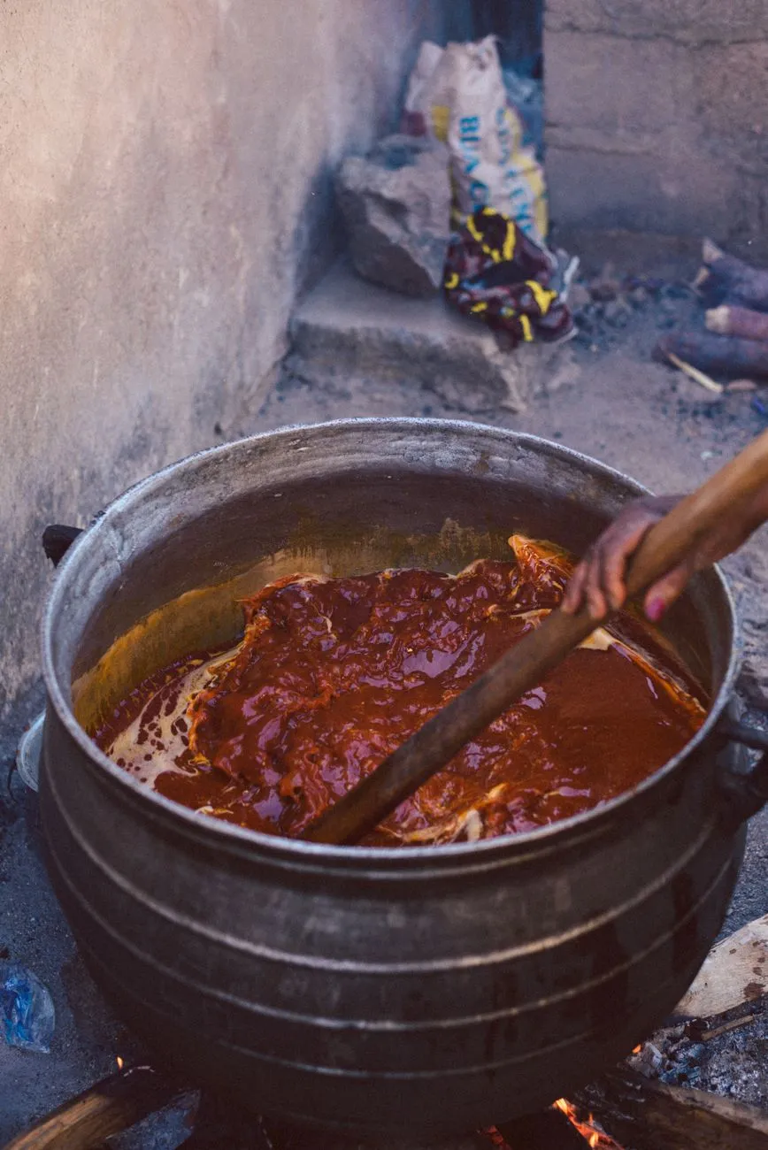 A steaming pot of Jollof rice surrounded by fried plantains and grilled chicken
