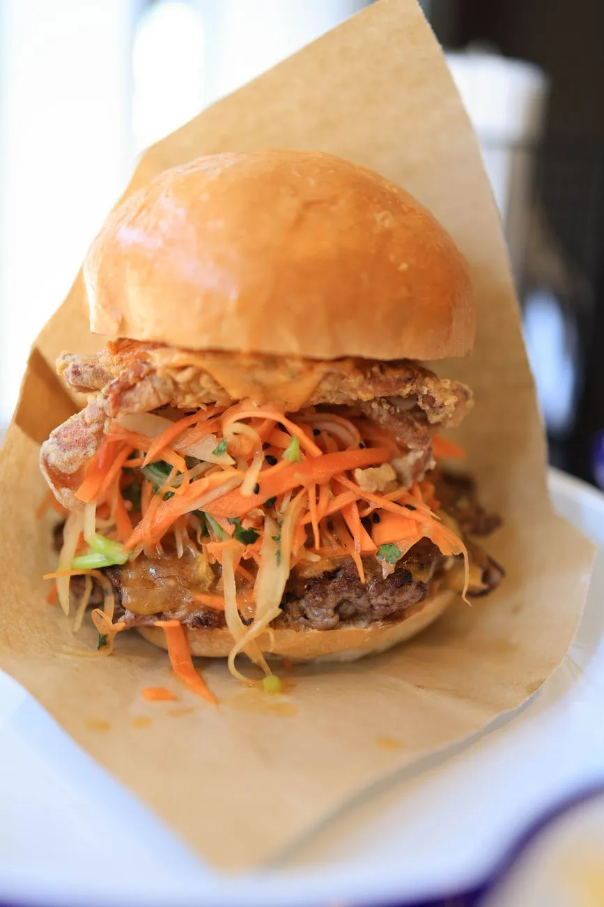 A colorful plate of a Japanese teriyaki burger with shredded cabbage and sesame seeds