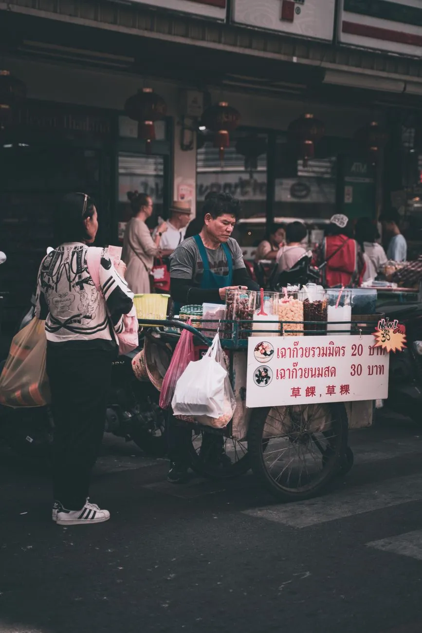 A bustling Bangkok street food stall with sizzling woks and steaming bowls