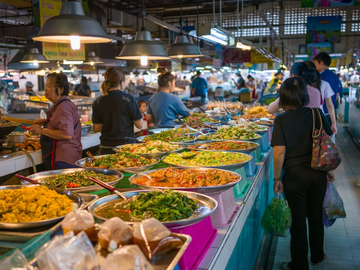 A vibrant night market with colorful food stalls and crowds of people