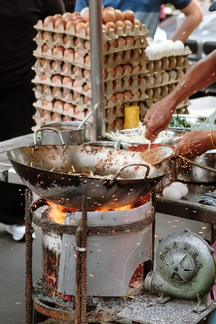 A chef preparing pad thai at a street food stall