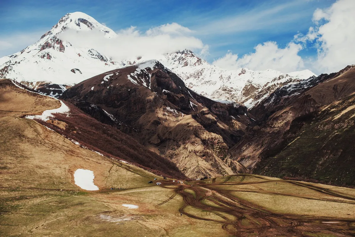 Hiker standing on a rocky outcrop in Truso Valley Georgia with snow-capped peaks in the background