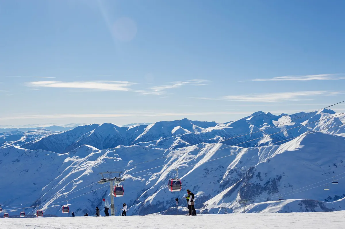 Skiers on a snowy slope in Gudauri Georgia with Caucasus Mountains in the background