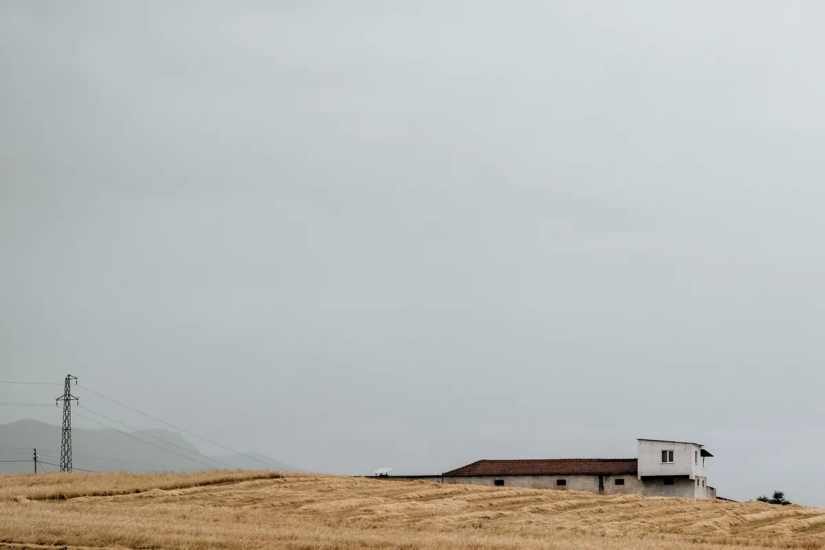 A lonely house on a desolate hill under a grey sky