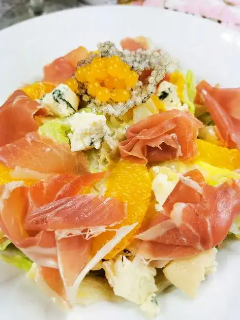 Insalata gourmet di farro perlato con verdure colorate, erbe fresche e feta su un tavolo di legno rustico