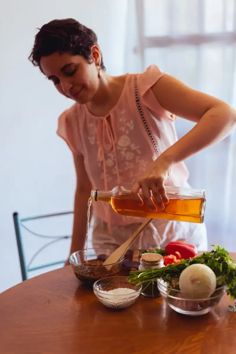 Giovane donna prepara un'insalata fresca con verdure biologiche e condimento all'olio d'oliva in una cucina luminosa
