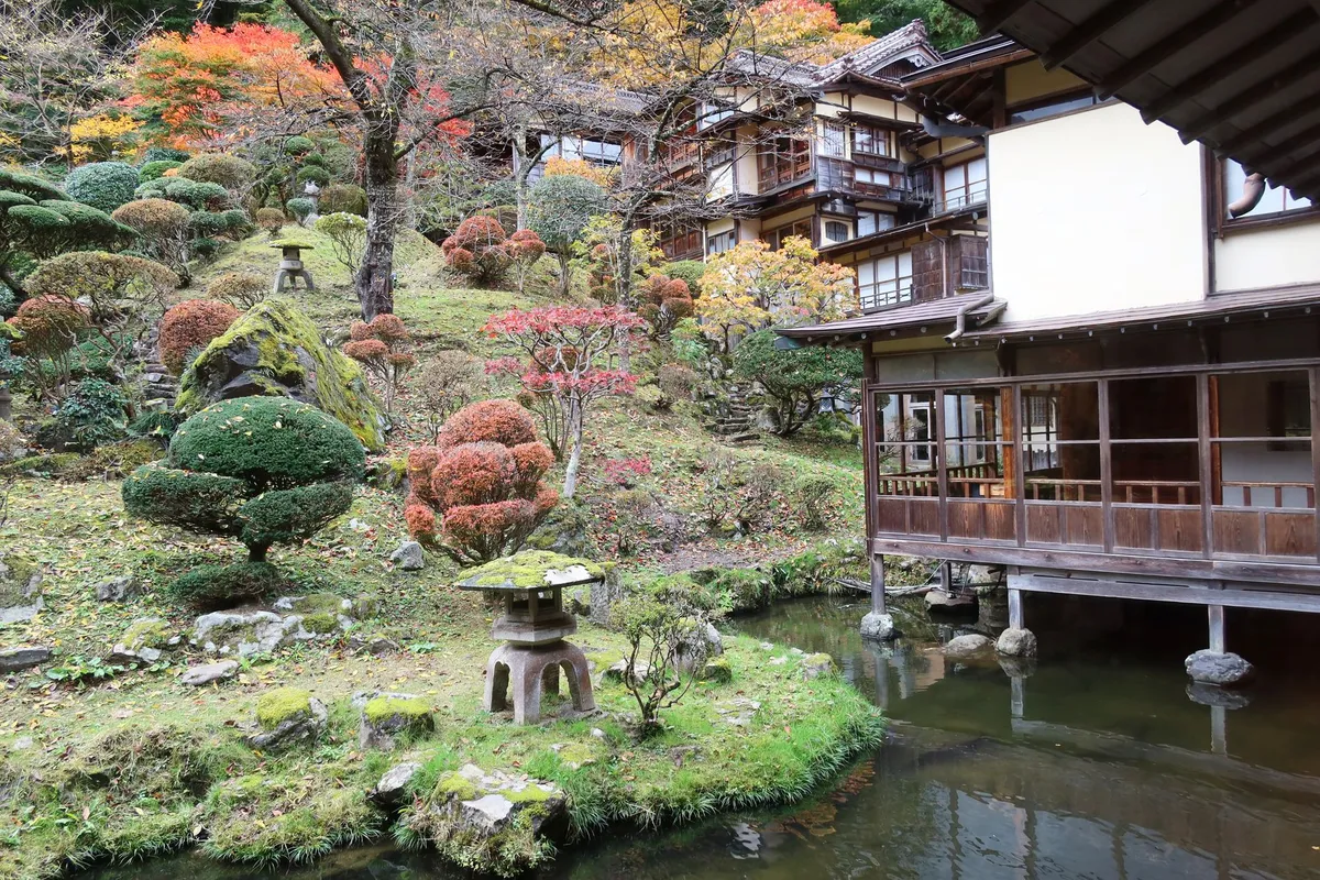 A secluded wooden ryokan nestled in a lush forest, with a private outdoor onsen steaming in the foreground