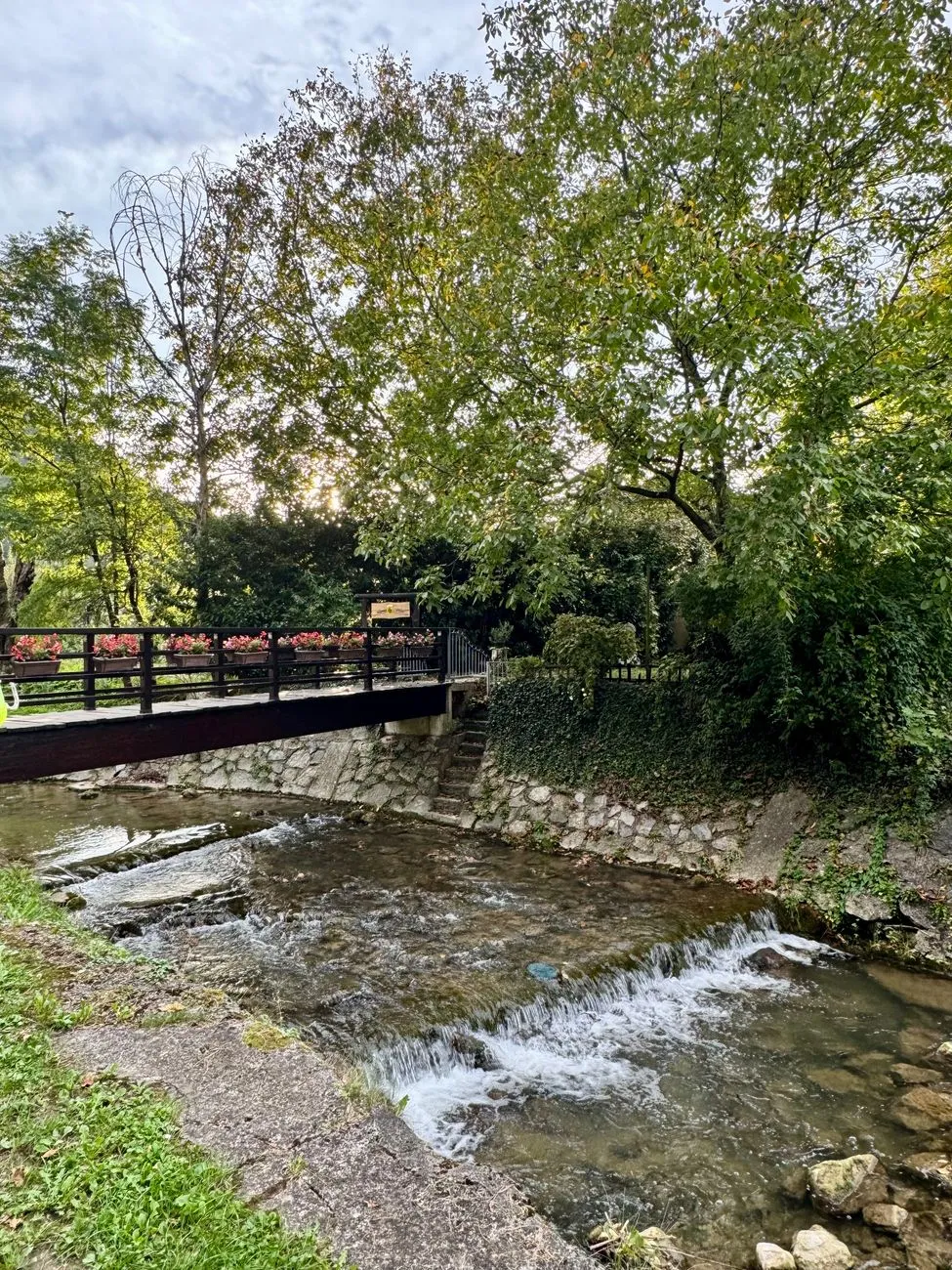 A traditional wooden footbridge over a river in Kurokawa Onsen, with ryokan lining the banks