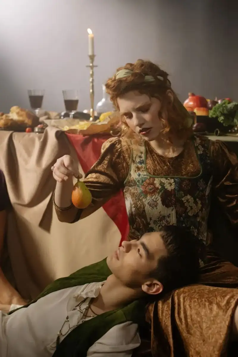 Scène d'un festin médiéval français, table abondante, viandes rôties, fruits, pain, chandeliers et convives en costumes d'époque