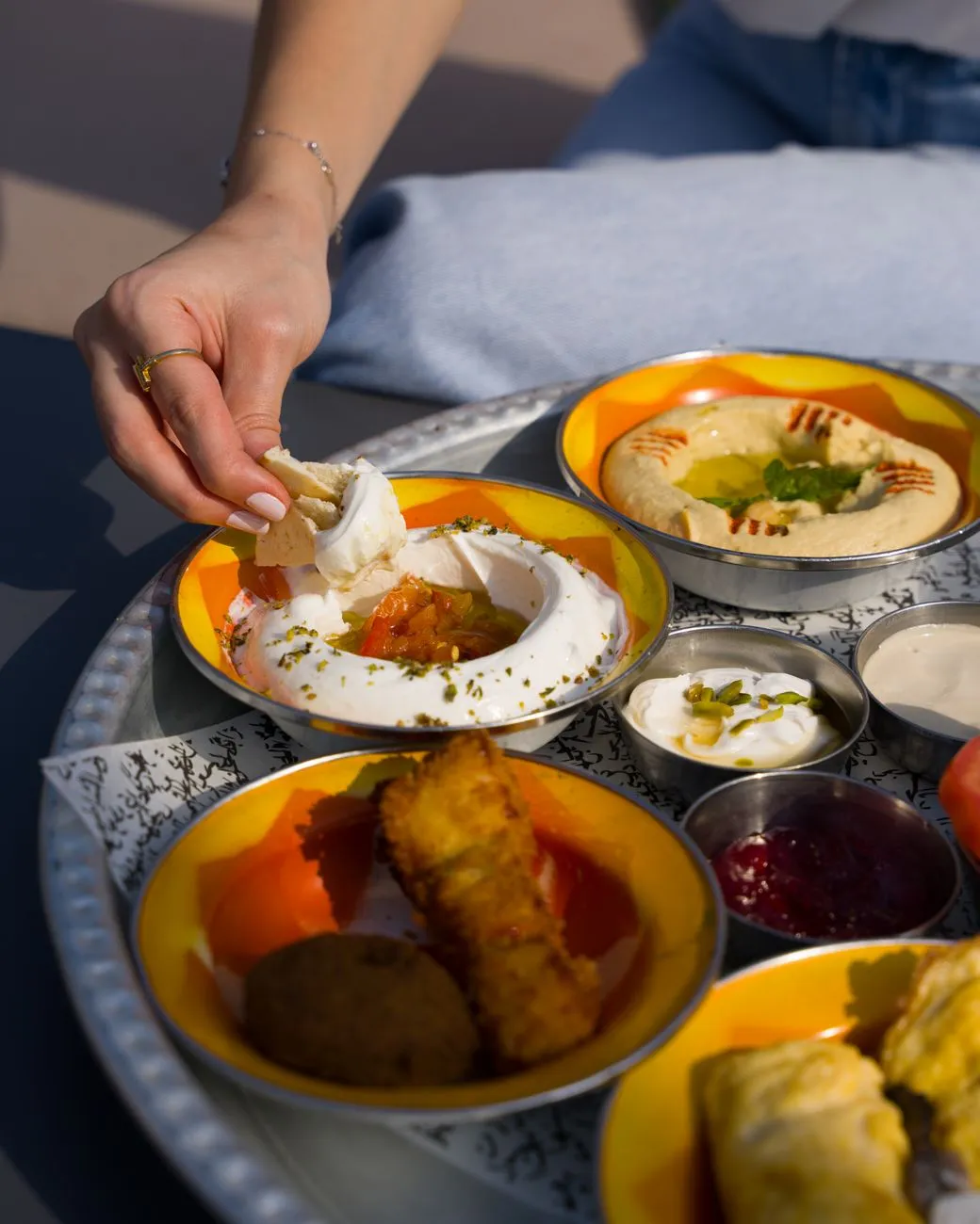 A person dipping pita into a bowl of hummus