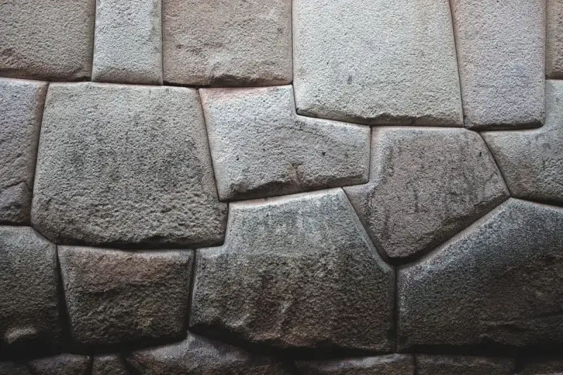 Détails de maçonnerie inca à sec, pierres parfaitement ajustées, ingénierie antique, lumière du soleil sur la roche texturée, architecture andine