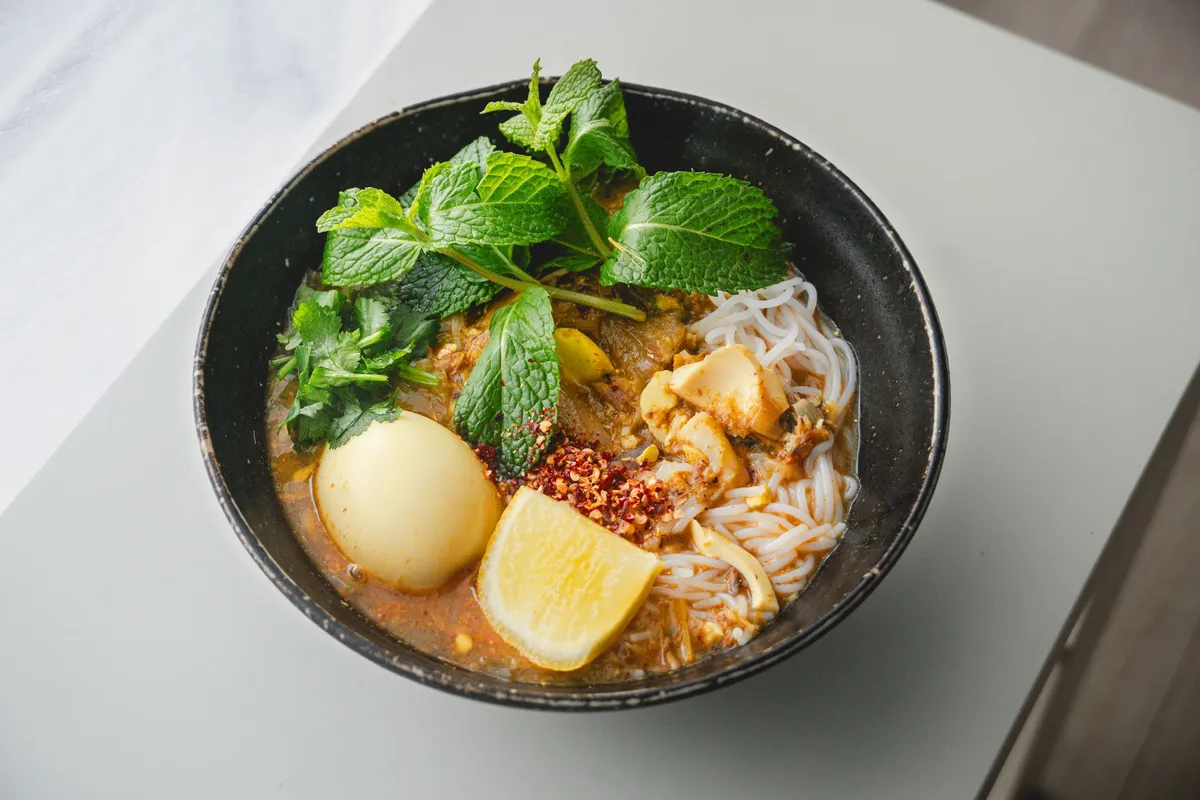 Close-up of Asam Laksa with fish and herbs