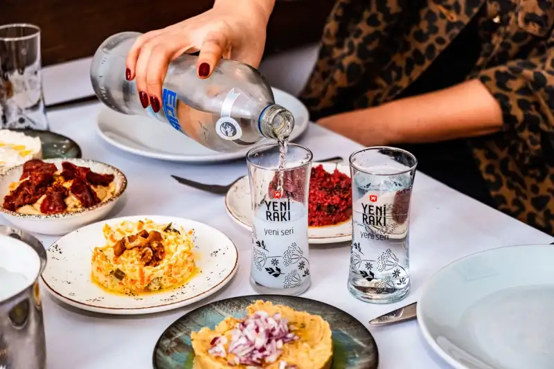 A glass of arak with mezze dishes in the background
