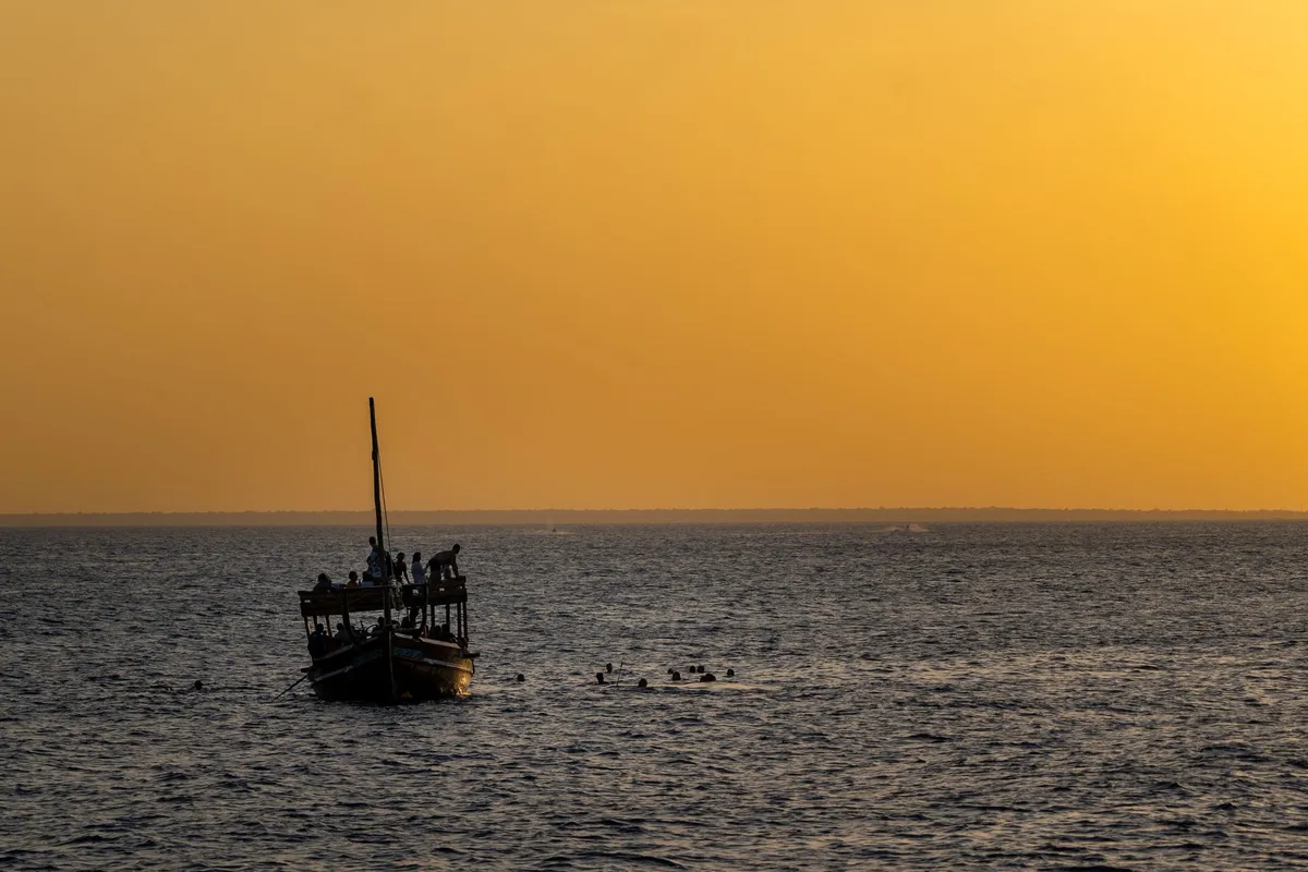 A traditional Omani boat, or dhow, sailing into the sunset