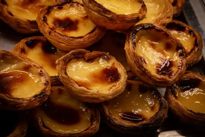 A colorful display of modern Pastéis de Nata variations, including salted caramel and chocolate