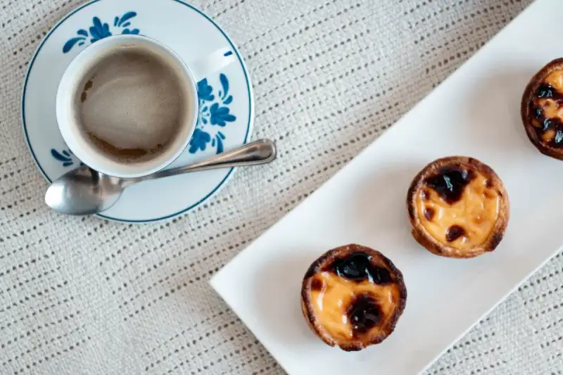 A split image showing a traditional Pastel de Nata next to a lighter, mini version