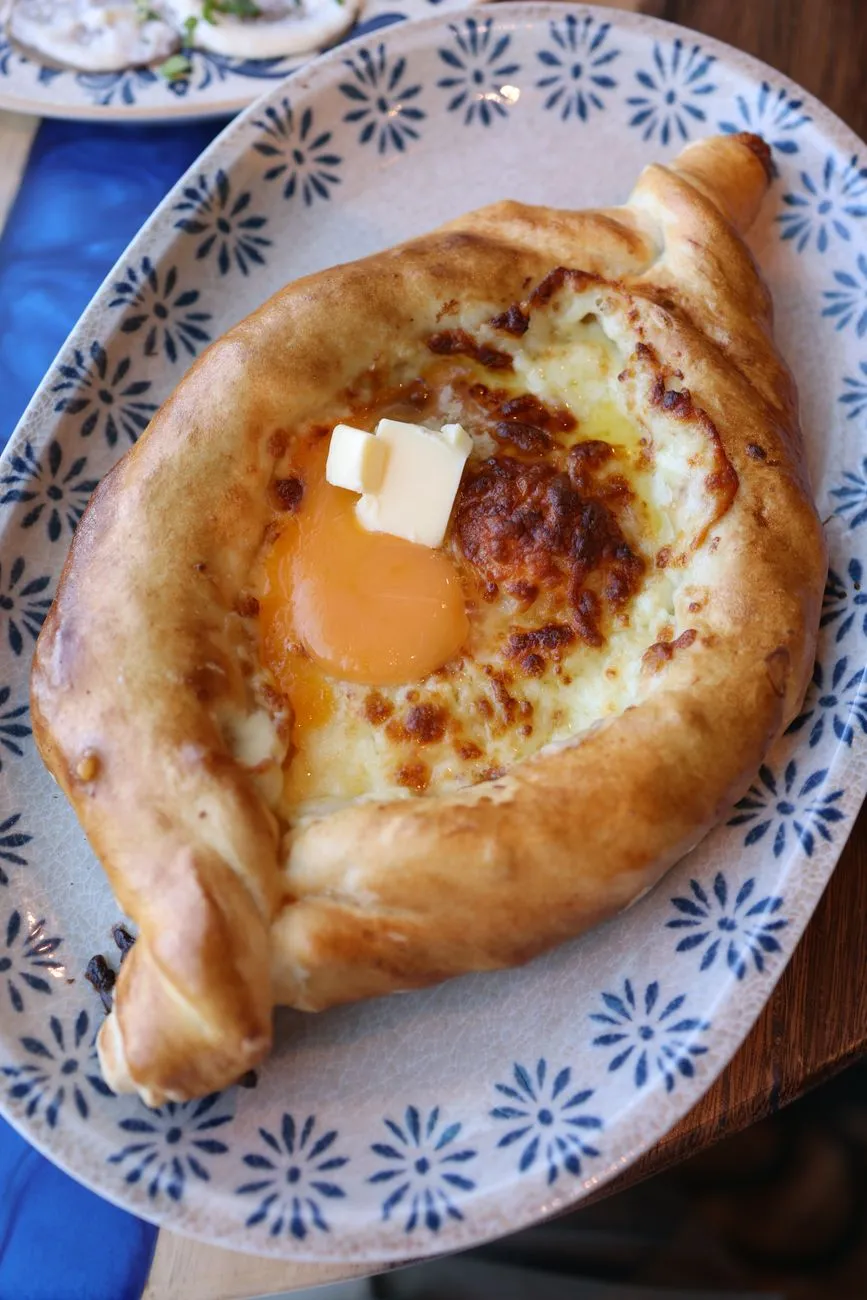 Round Imeruli khachapuri with golden crust and cheese pull