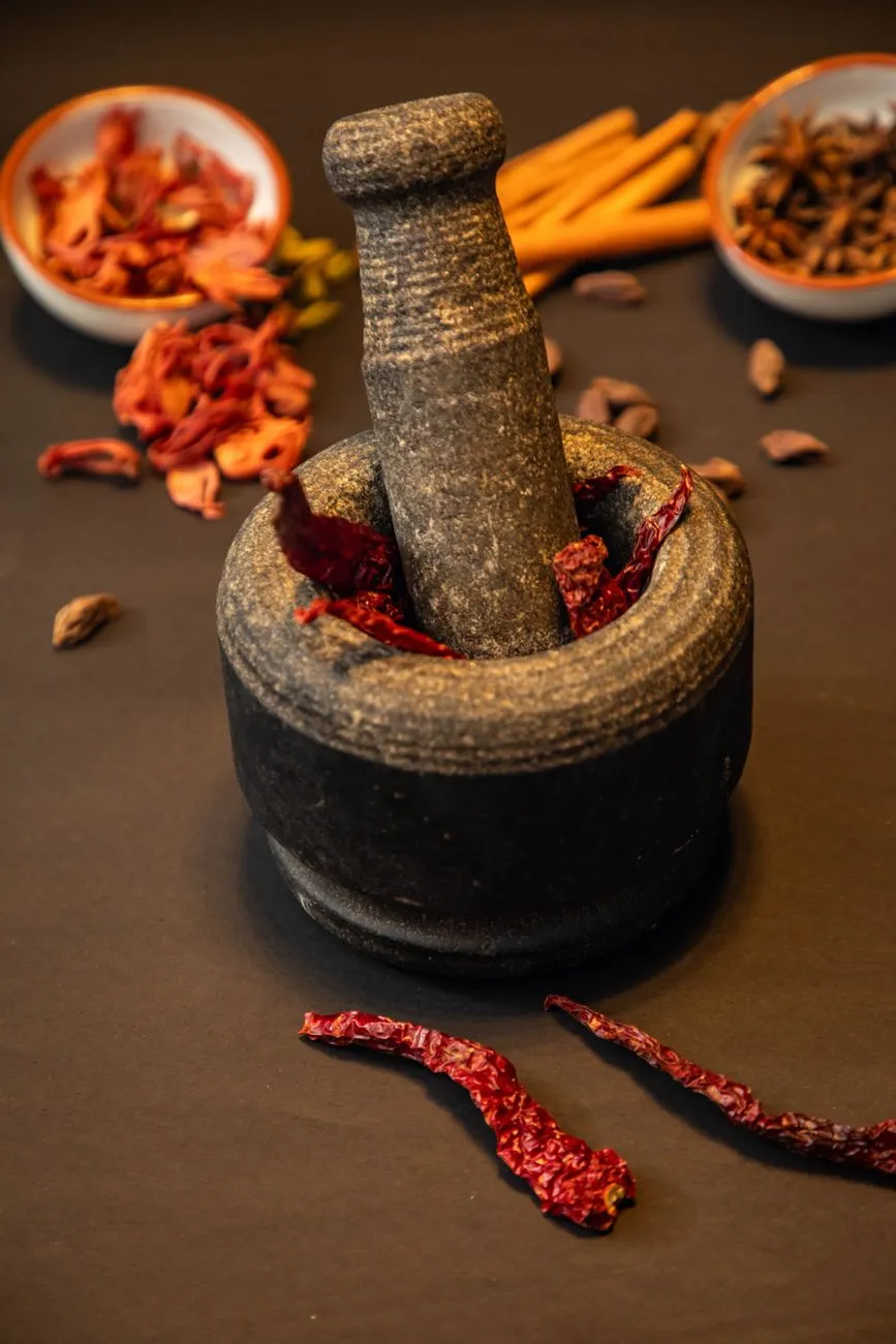 A close-up of a mortar and pestle grinding spices for a South Indian curry