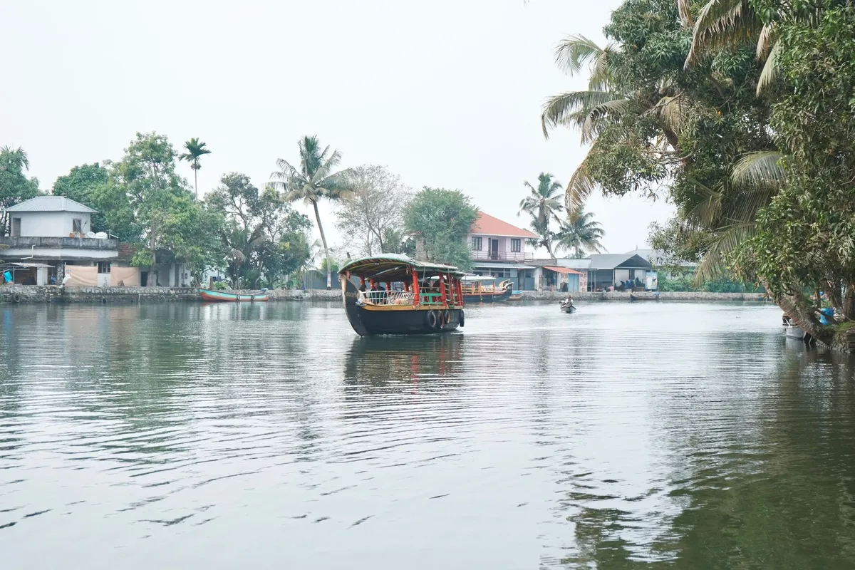 A lush Kerala backwater with coconut trees and traditional houseboats