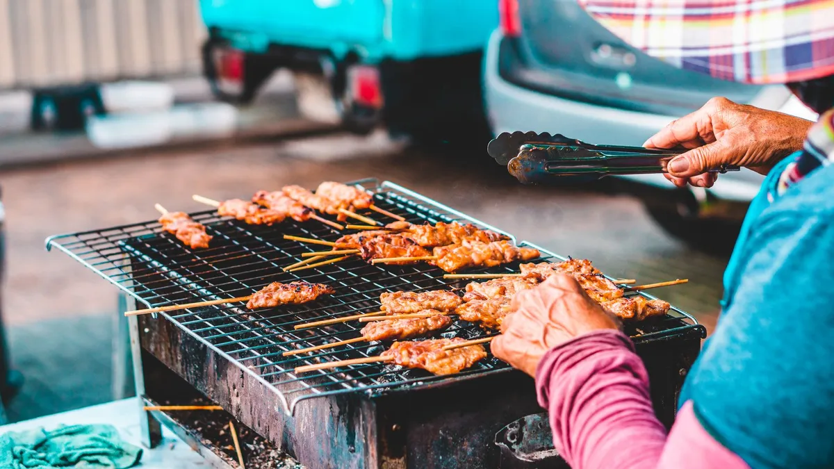 A bustling street food stall in Bangkok with grilled prawns and spicy dipping sauces