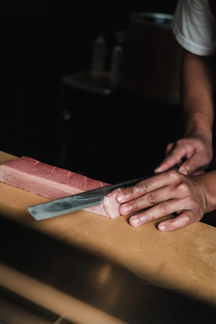 A sushi chef preparing fresh tuna at a market stall in Tokyo