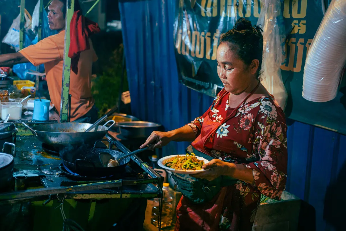 Senegalese woman frying accras in a bustling market
