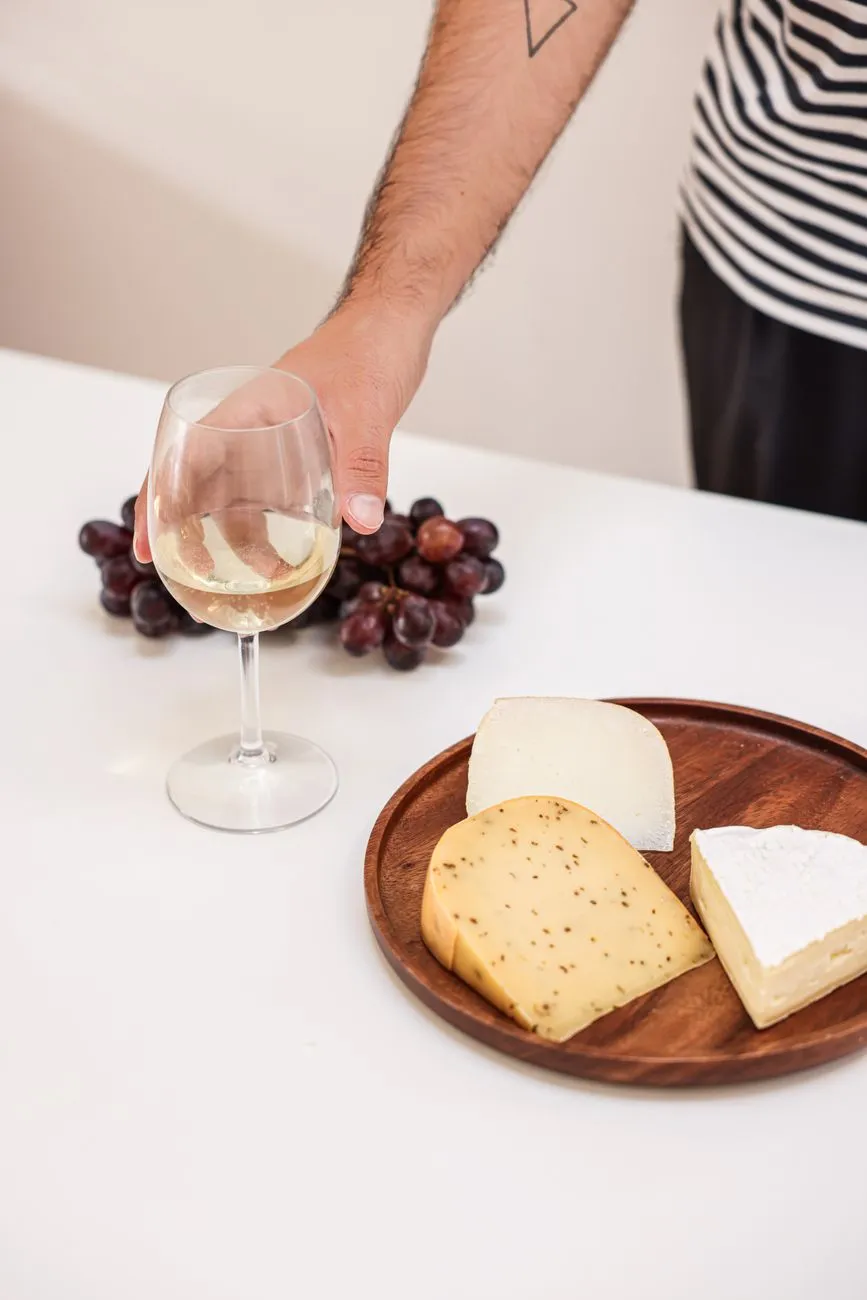 A cozy dining table set for a French wine and cheese tasting, with wine glasses, cheese knives, and a baguette