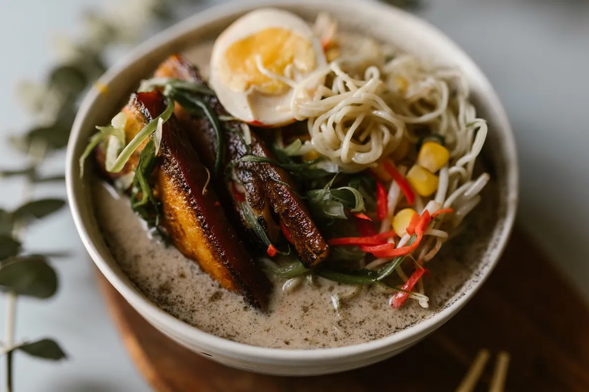 A steaming bowl of tonkotsu ramen with thick white broth, chashu pork, and green onions