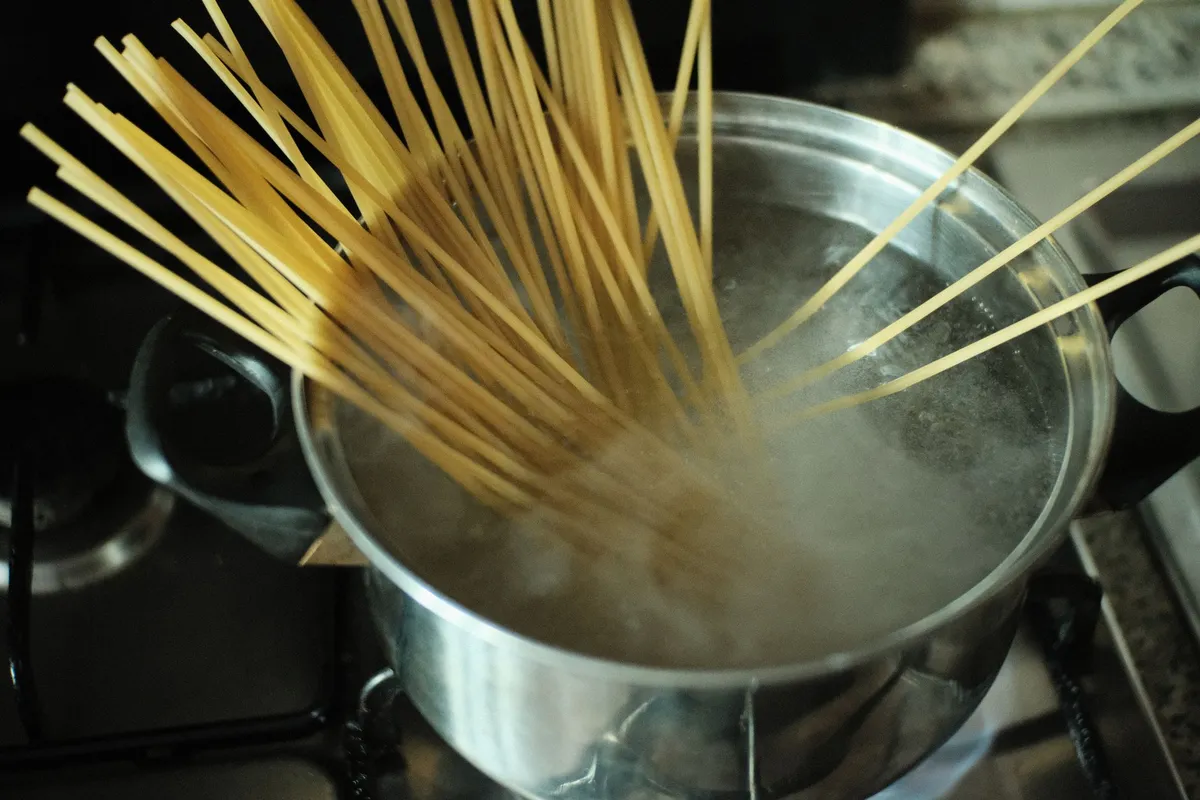 A close-up of ramen noodles being pulled from a pot of boiling water