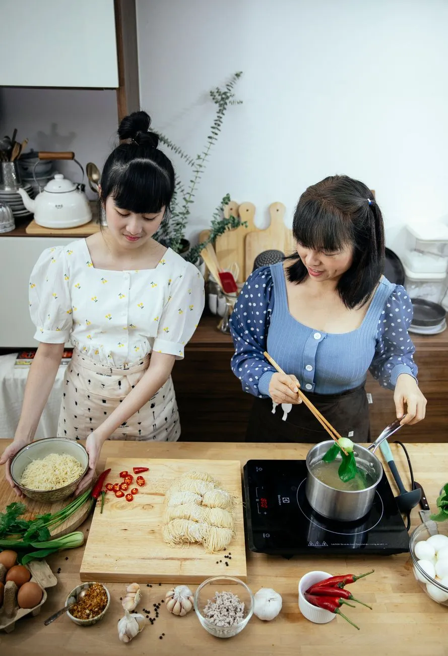 A home cook arranging ramen toppings on a wooden table