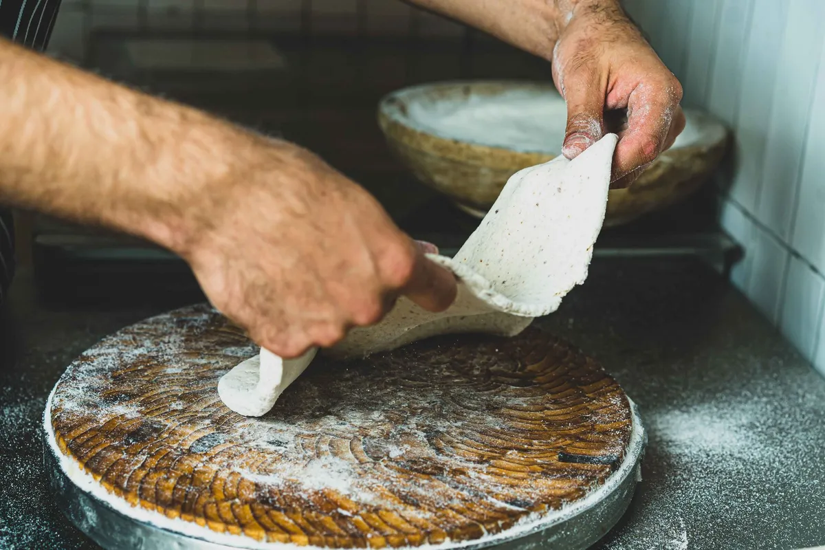 Sourdough pizza dough being stretched