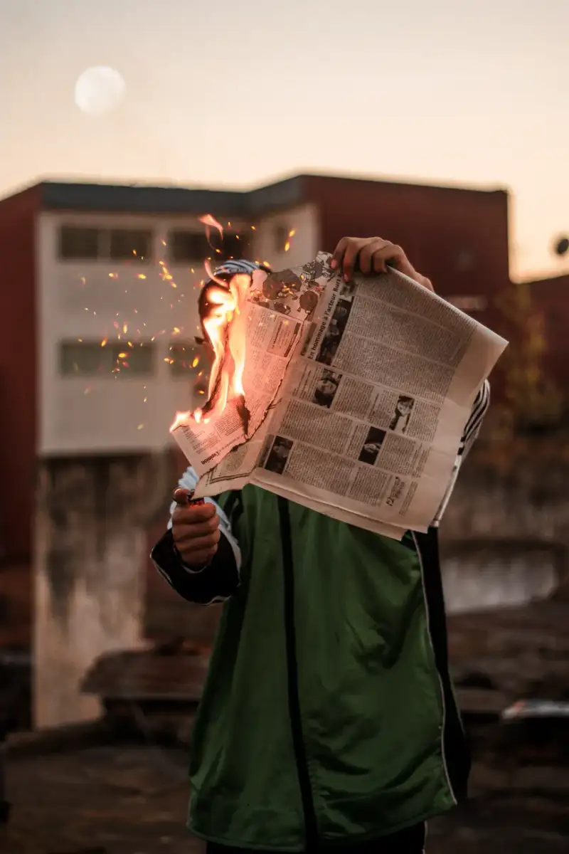 Mani che reggono un libro tra le fiamme, metafora della resistenza