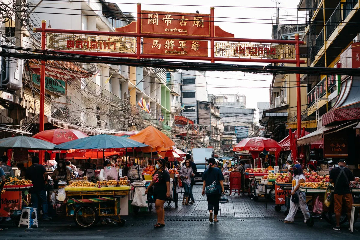 A bustling Bangkok street food market with vendors and customers