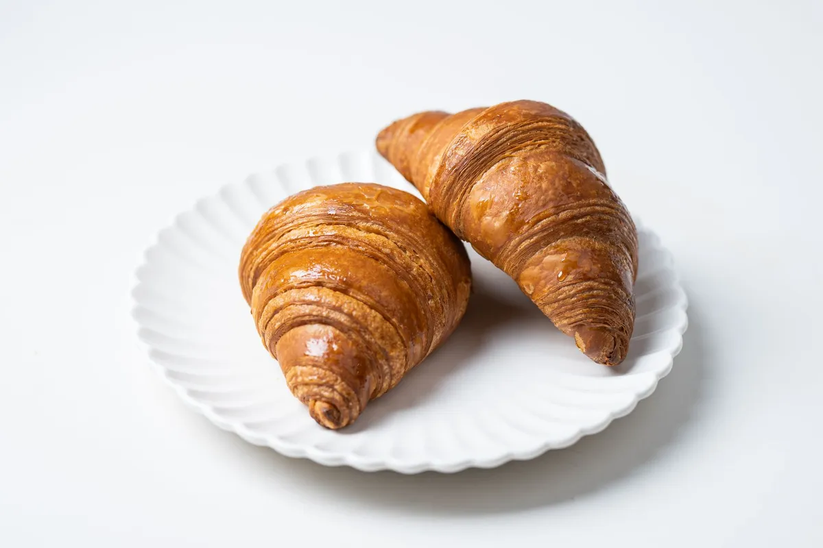 A delicate close-up of a golden, flaky croissant layer revealing its complex interior structure