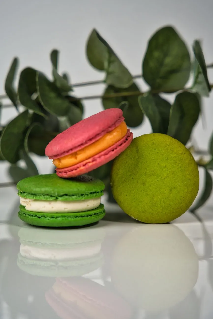 Vibrantly colored macarons stacked elegantly on a marble countertop with almond dust nearby
