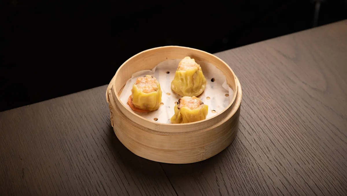 A steaming bamboo steamer filled with har gow and siu mai