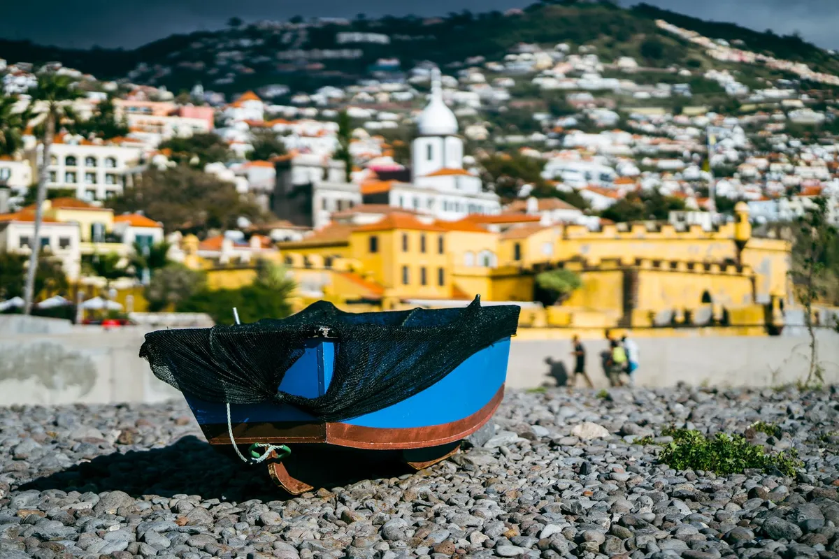 Colorful boats in a harbor with a traditional Azorean building in the background
